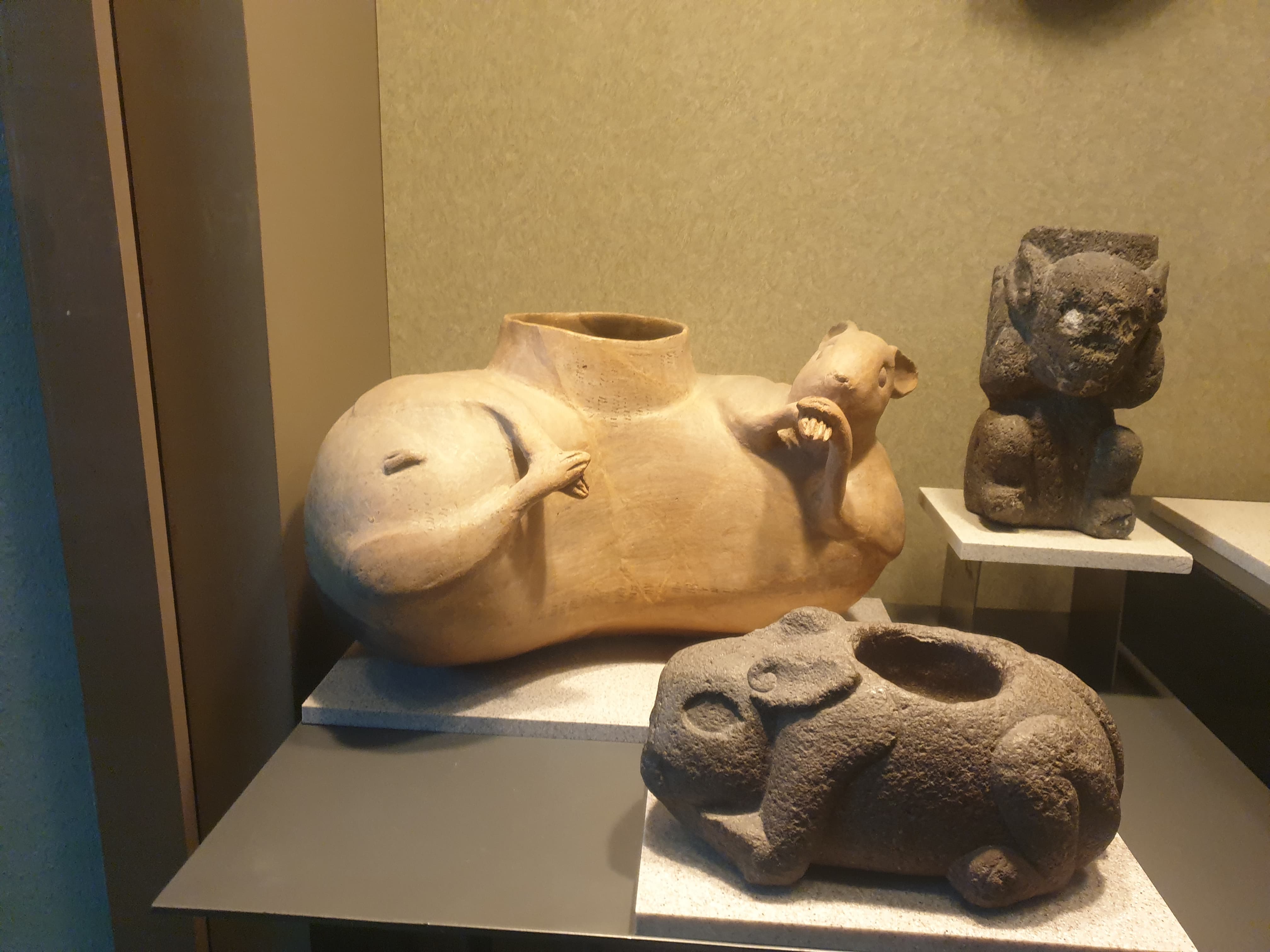 An Early Postclassic ceramic effigy vessel in the form of an animal lying on its back, its belly opened into a vessel mouth, beside a carved stone rabbit with a bowl cut into its spine.